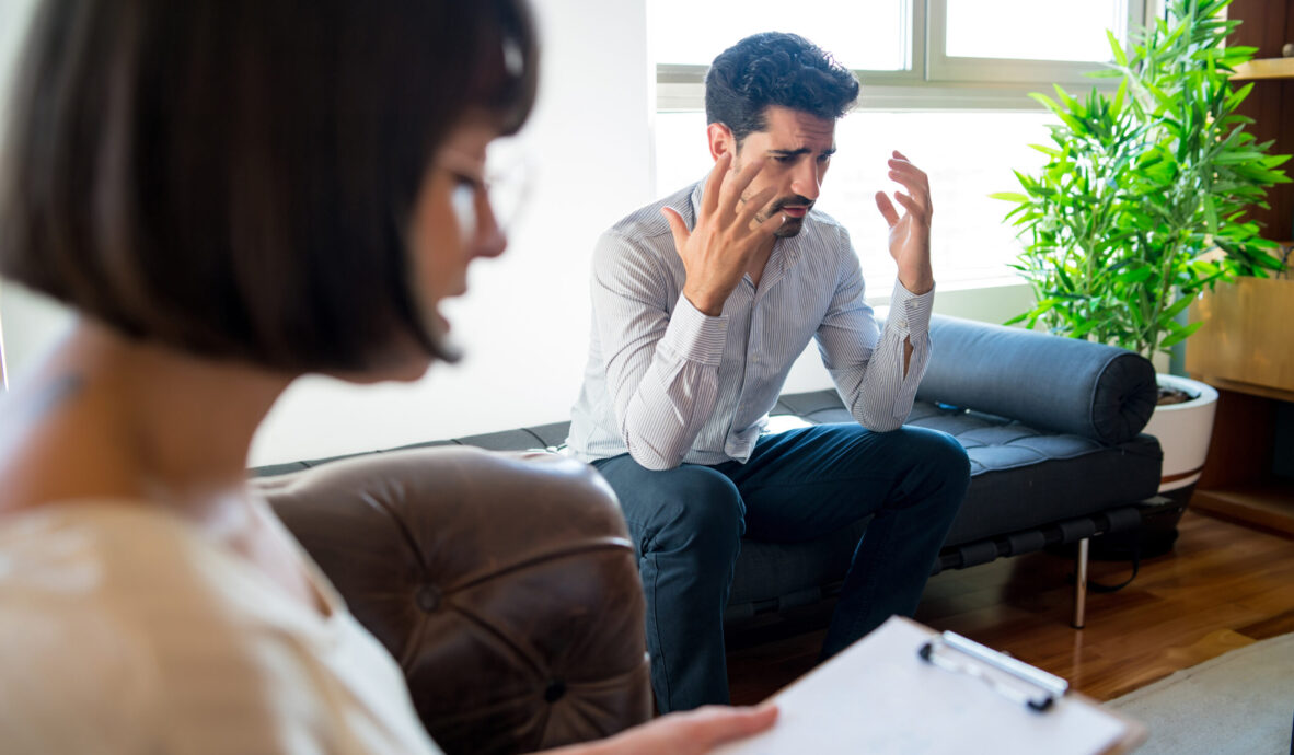 Close-up of a psychologist taking notes on clipboard during therapy session with her worried patient. Psychology and mental health concept.